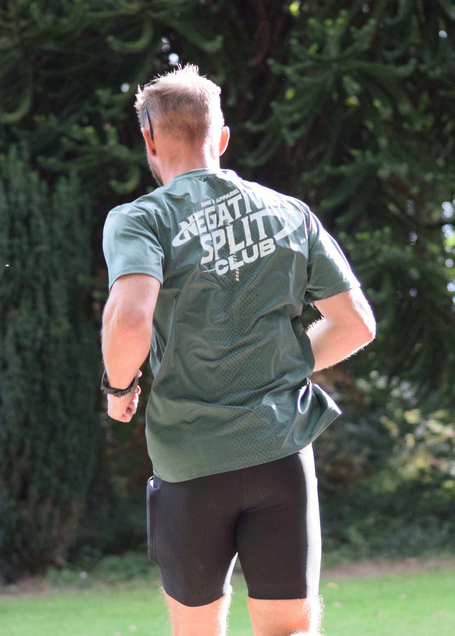 Negative Split Club Premium Running Tee in Green as the model runs away from the camera