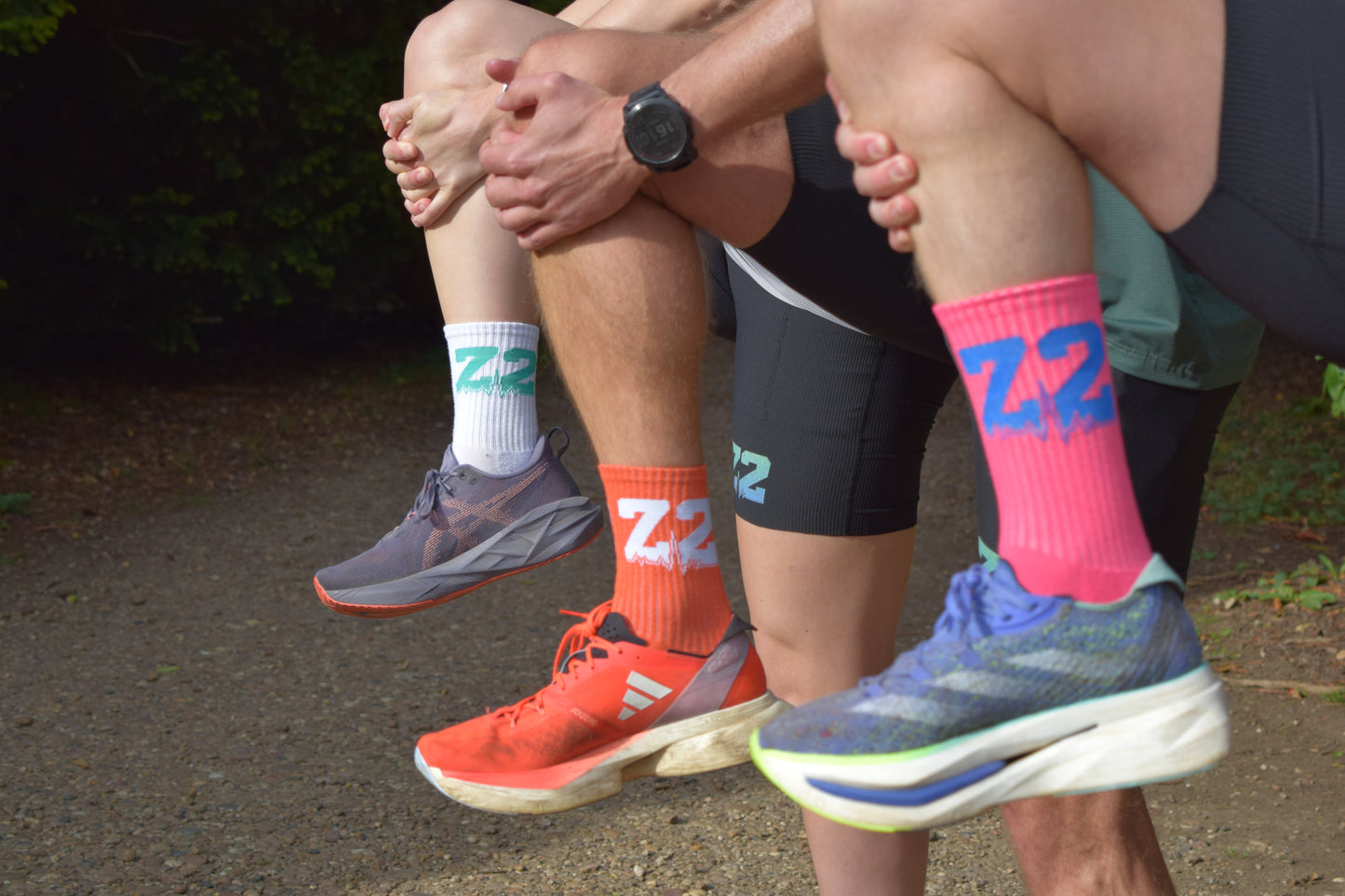 Group shot of individuals wearing the comfortable Vantage Running sock, displayed in Pink, Orange and White