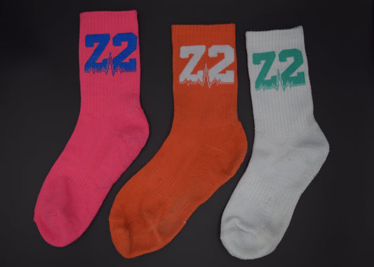 Group shot of the comfortable Vantage Running sock, displayed in Pink, Orange and White against a black background.