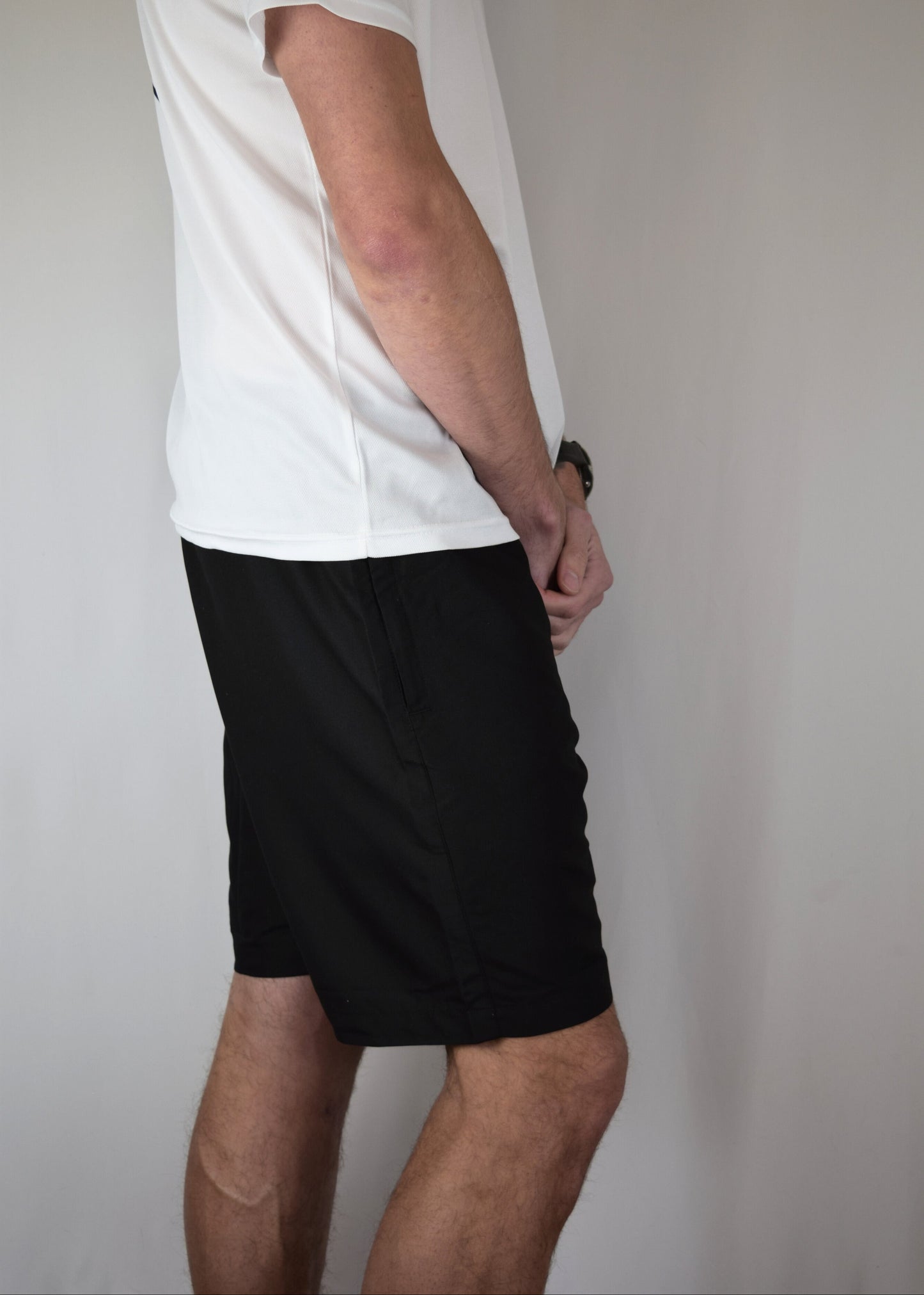 Man wearing comfortable black athletic shorts with 'Z2' logo and a white shirt with a visible brand logo on a plain background