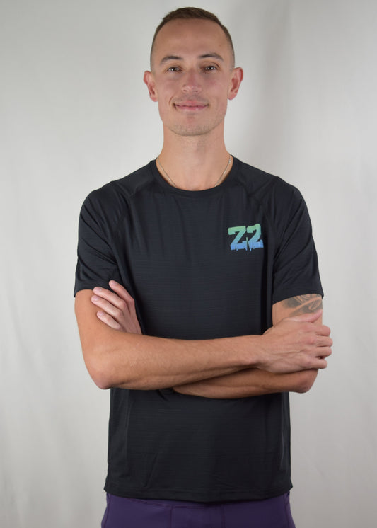 The Mantra Technical Running Tee in black, from the front. Model is standing with his arms crossed