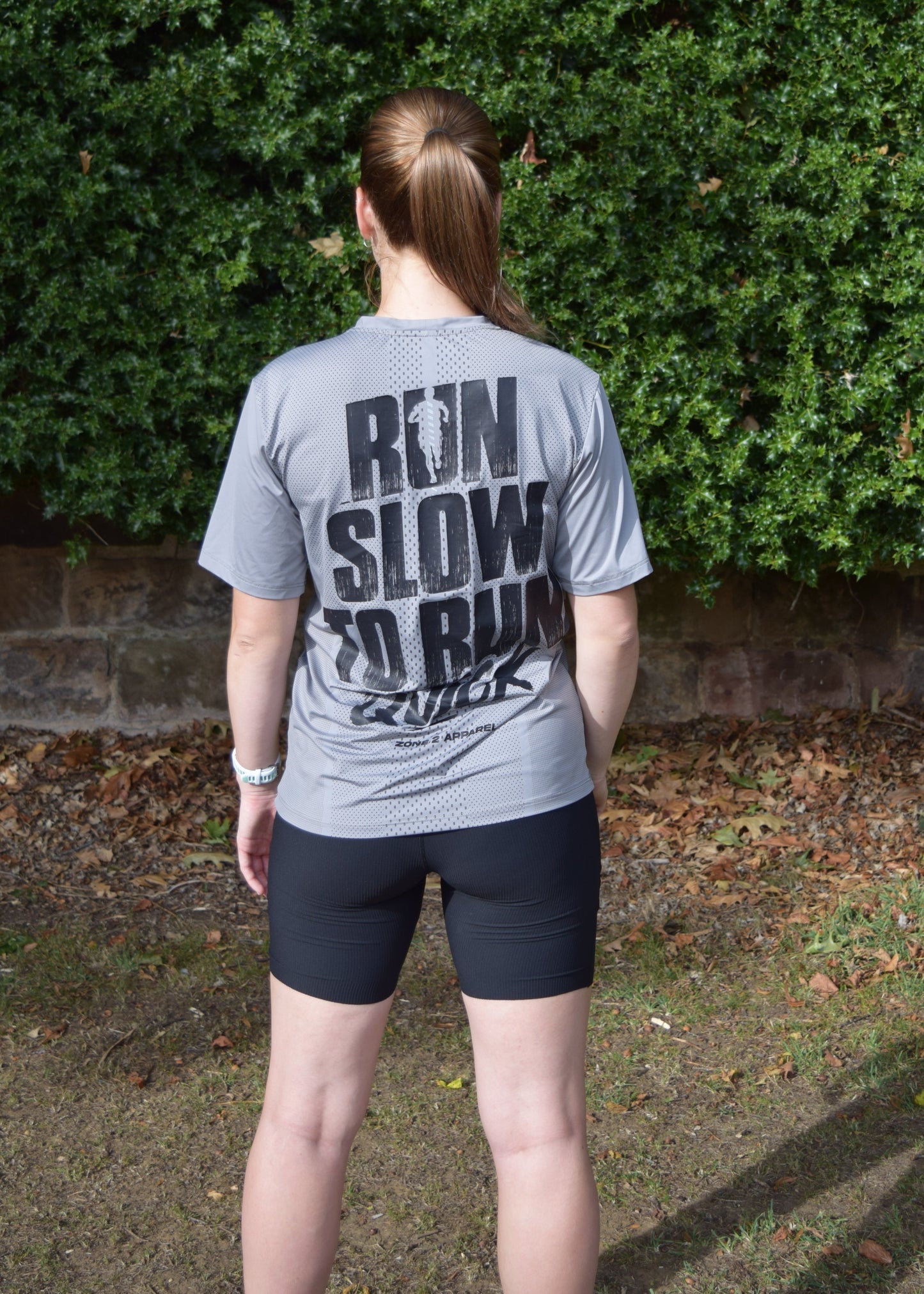 The Mantra tee in grey being worn by a female model, facing away from the camera