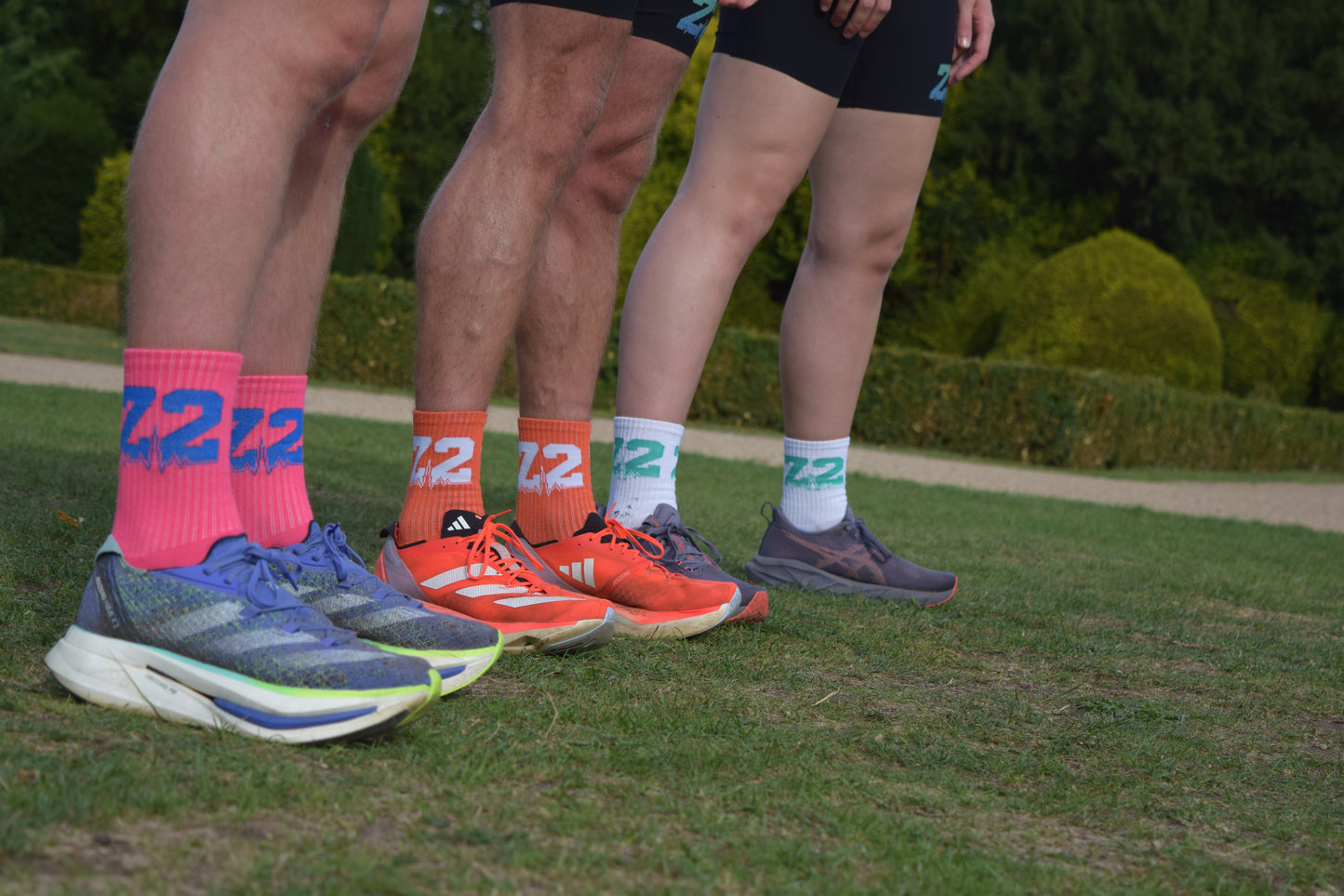 Group shot of individuals wearing the comfortable Vantage Running sock, displayed in Pink, Orange and White