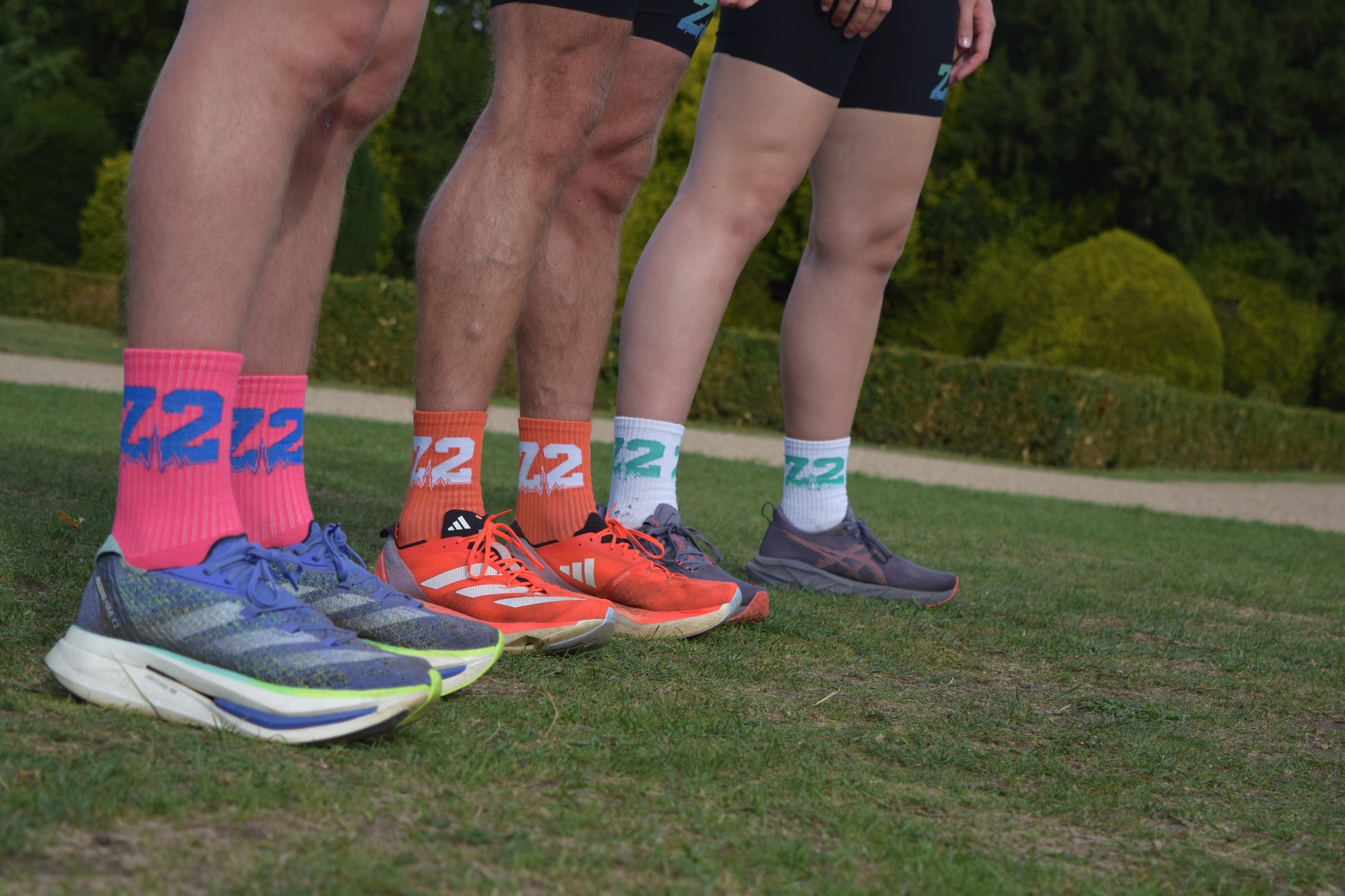 Group shot of individuals wearing the comfortable Vantage Running sock, displayed in Pink, Orange and White