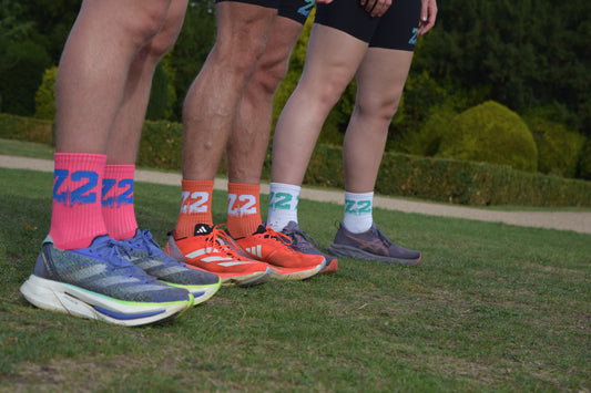Group shot of individuals wearing the comfortable Vantage Running sock, displayed in Pink, Orange and White